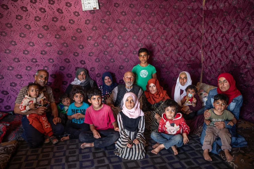 Jassim (centre) with several generations of his family in the tent they have pitched on the site where their home once stood. © UNHCR/Hameed Maarouf