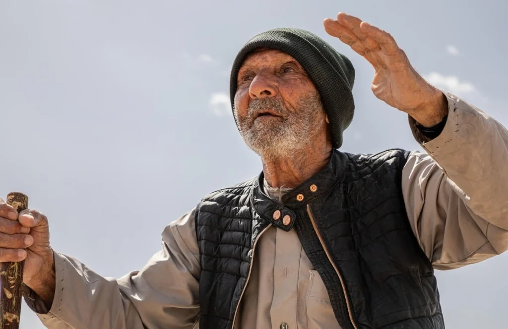 Jassim, a 103-year-old Syrian returnee, stands beside the ruins of his former home in the countryside around Al-Qusayr, in the Homs Governorate. © UNHCR/Hameed Maarouf