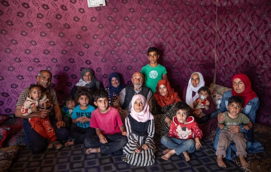 Jassim (centre) with several generations of his family in the tent they have pitched on the site where their home once stood. © UNHCR/Hameed Maarouf