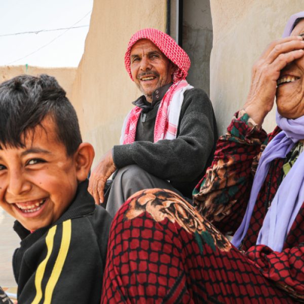 Shahada Al-Daais, 65, sits with his wife and son outside their rehabilitated home in rural southern Aleppo. © UNHCR/Hameed Maarouf