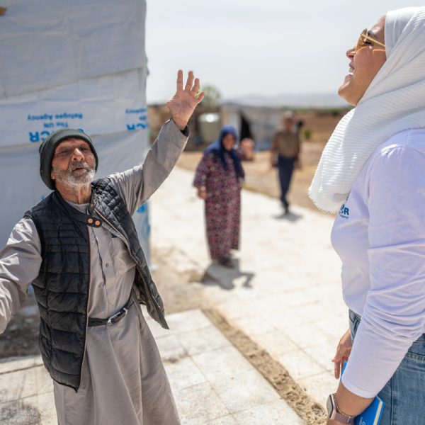 Jassim speaks with a UNHCR staff member outside his tent in Al-Qusayr, Homs governorate, Syria.