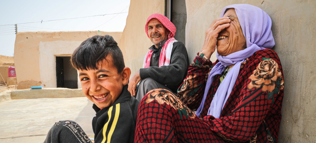 Shahada Al-Daais, 65, sits with his wife and son outside their rehabilitated home in rural southern Aleppo. © UNHCR/Hameed Maarouf